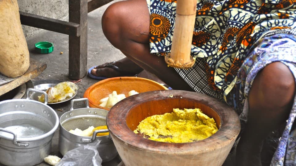 A woman prepares food using traditional Ghanaian methods